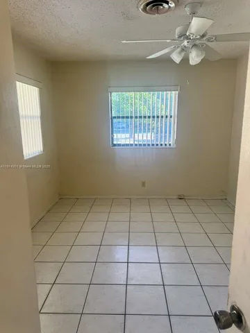 en empty room with windows and ceiling fan