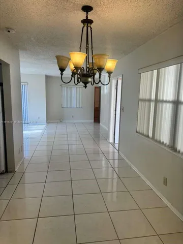 a view of a room with a chandelier fan and kitchen view