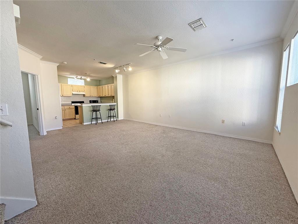 an empty room with chandelier fan and windows