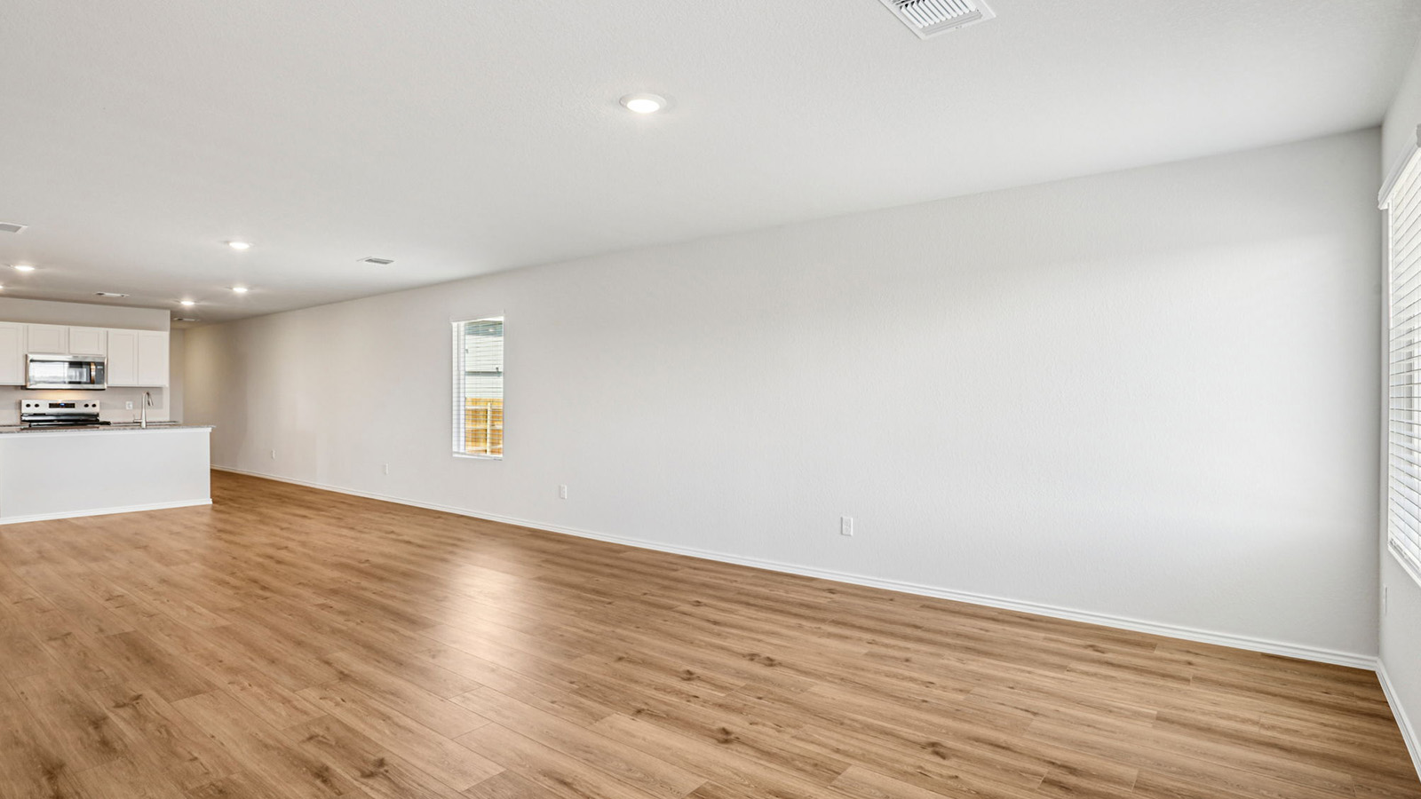 148 Wyatt Way Jarrell, TX 76537 - Photo 11 of 33 Open-concept living space featuring wood-finish flooring, recessed lighting, and a kitchen with white cabinetry, stainless steel appliances, and a breakfast bar