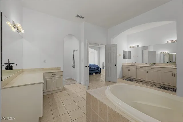 a spacious bathroom with a tub sink and mirror