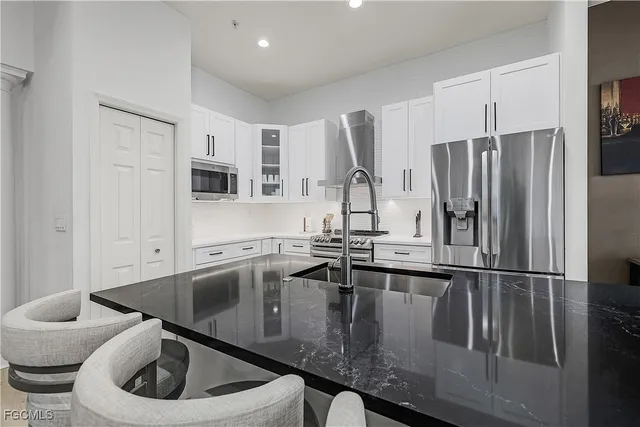 a kitchen with stainless steel appliances granite countertop a sink a microwave a refrigerator and white cabinets