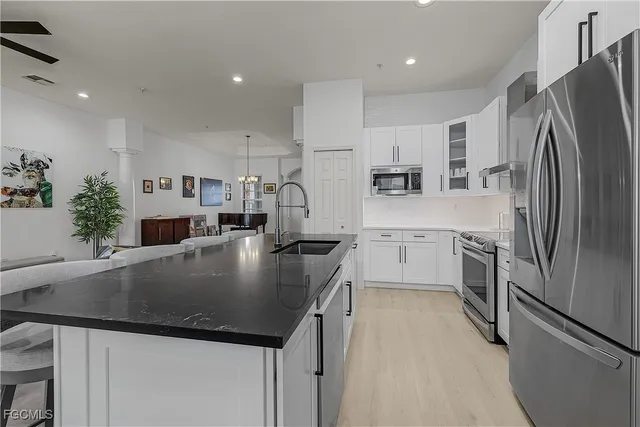 a kitchen with stainless steel appliances granite countertop a refrigerator a sink a stove a microwave and a refrigerator