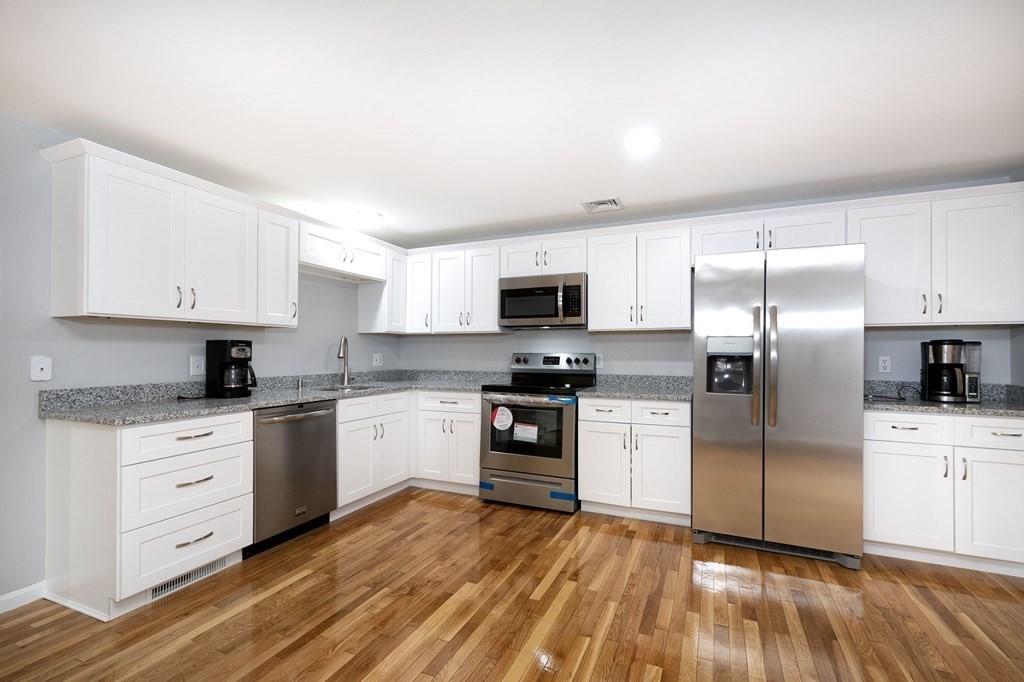 213 Beaver Dam Road Scituate, MA 02066 - Photo 3 of 28 a kitchen with granite countertop a refrigerator oven a sink dishwasher and a stove top oven with wooden floor