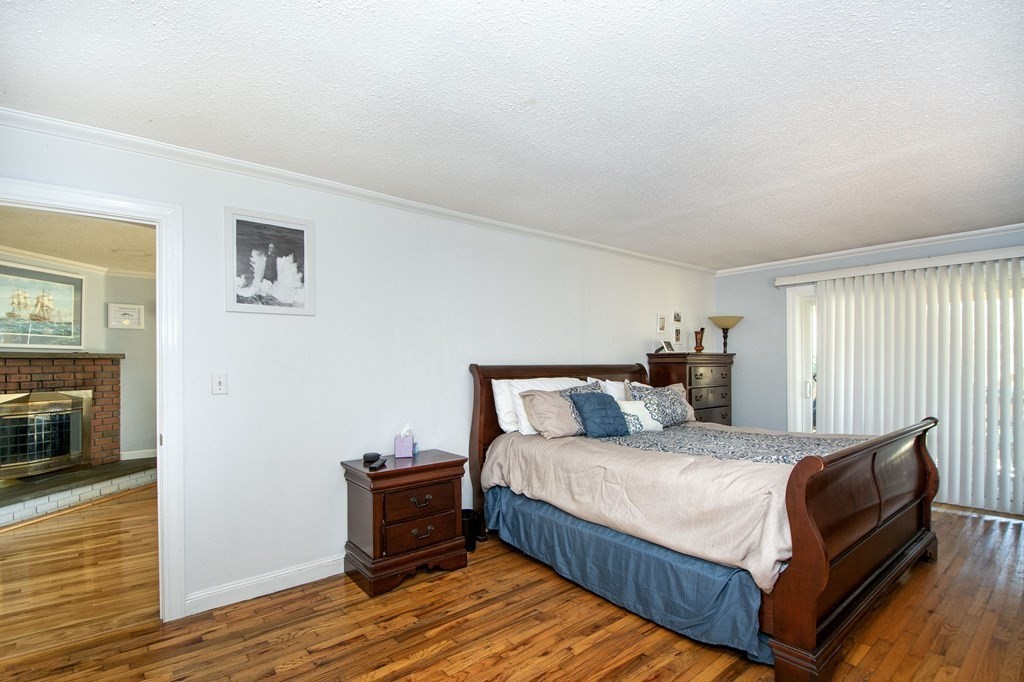 213 Beaver Dam Road Scituate, MA 02066 - Photo 9 of 28 a bedroom with a bed and a fireplace