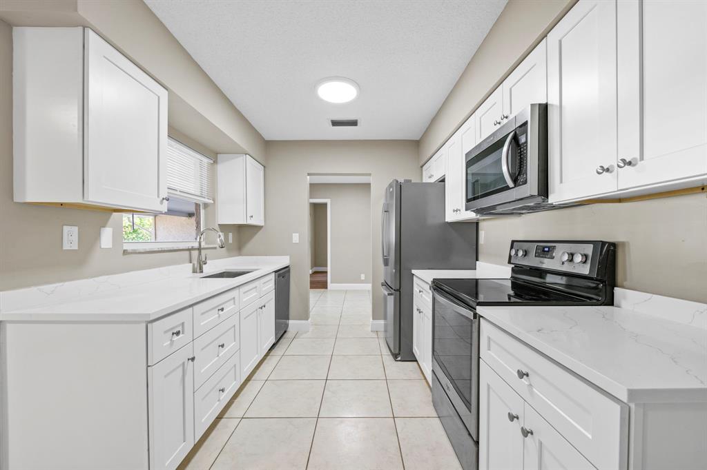 9203 Northwest 71st Street Tamarac, FL 33321 - Photo 5 of 23 a kitchen with stainless steel appliances granite countertop a sink and a stove