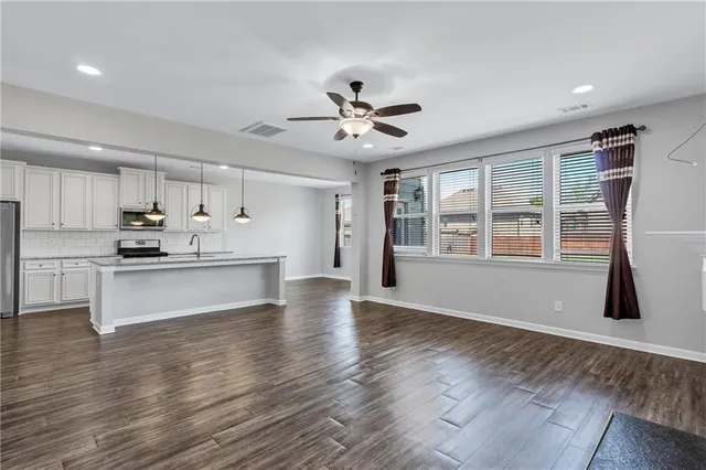 a view of kitchen counter top space with stainless steel appliances wooden floor and living room view