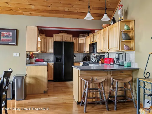 a kitchen with stainless steel appliances granite countertop a dining table chairs refrigerator and sink