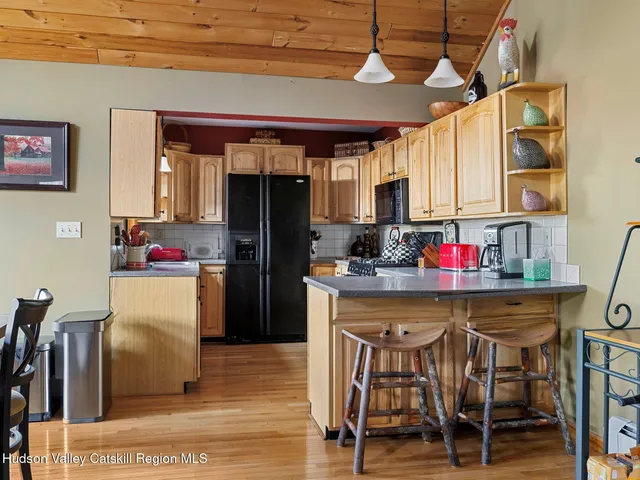 a kitchen with stainless steel appliances granite countertop a dining table chairs refrigerator and sink