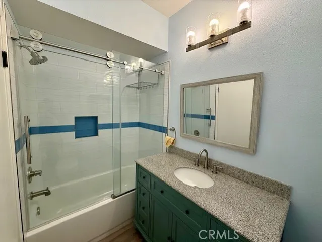 a bathroom with a granite countertop shower sink and mirror