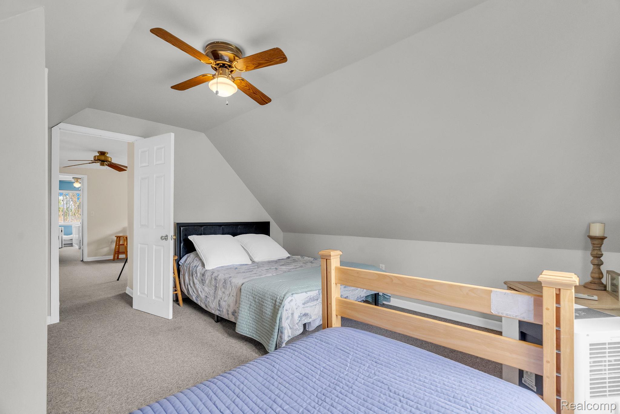 7489 Aspen Road Lexington, MI 48450 - Photo 47 of 62 Carpeted room featuring an angled ceiling, ceiling fan with light fixture, and a doorway leading to an additional space