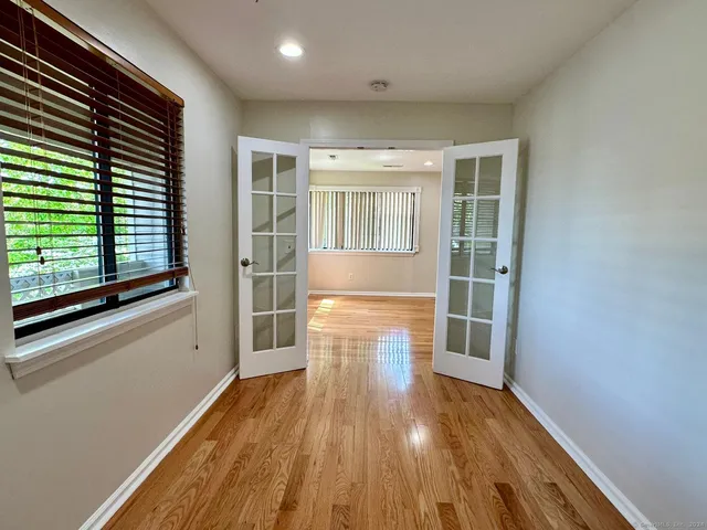 a view of empty room with wooden floor and fan