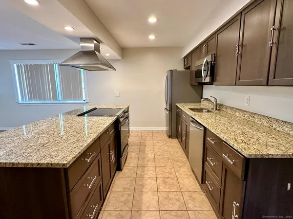 a kitchen with stainless steel appliances granite countertop a sink and a wooden cabinets