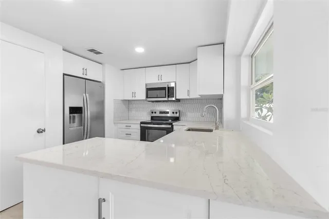 a kitchen with granite countertop a refrigerator and a stove top oven
