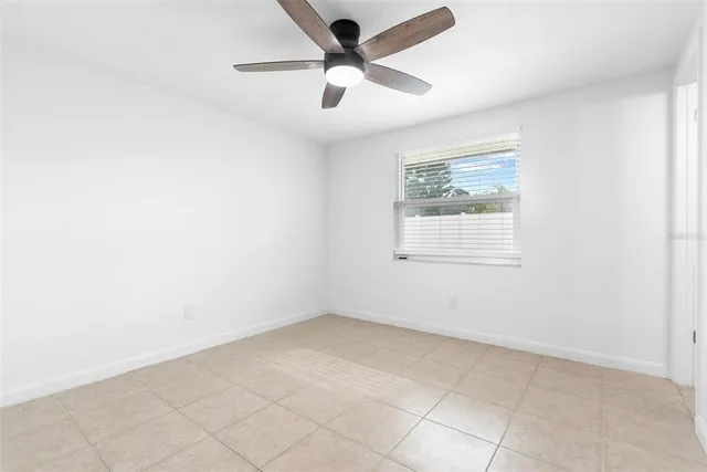 an empty room with a window and a fan
