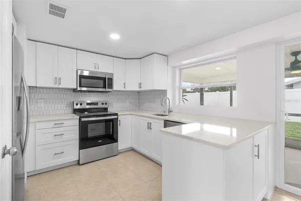 a kitchen with stainless steel appliances granite countertop a stove a sink and a microwave