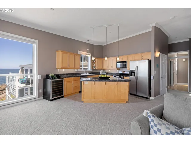 a kitchen with stainless steel appliances kitchen island granite countertop a refrigerator a stove a sink a dining table and chairs