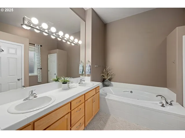 a bathroom with a sink double vanity granite tub and a mirror