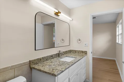 a bathroom with a granite countertop sink and a mirror