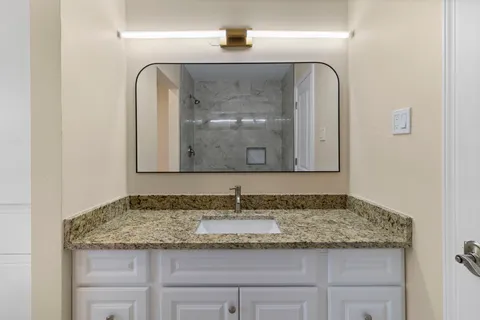 a bathroom with a granite countertop sink and a mirror