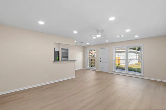 an empty room with wooden floor and windows