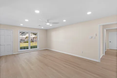 a view of an empty room with wooden floor and windows
