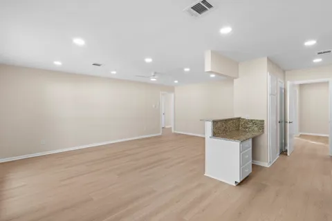 a view of kitchen and an empty room with wooden floor
