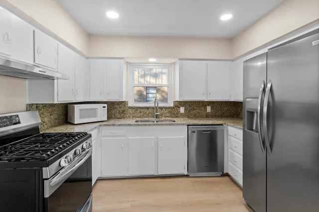 a kitchen with stainless steel appliances granite countertop a stove a refrigerator and a sink