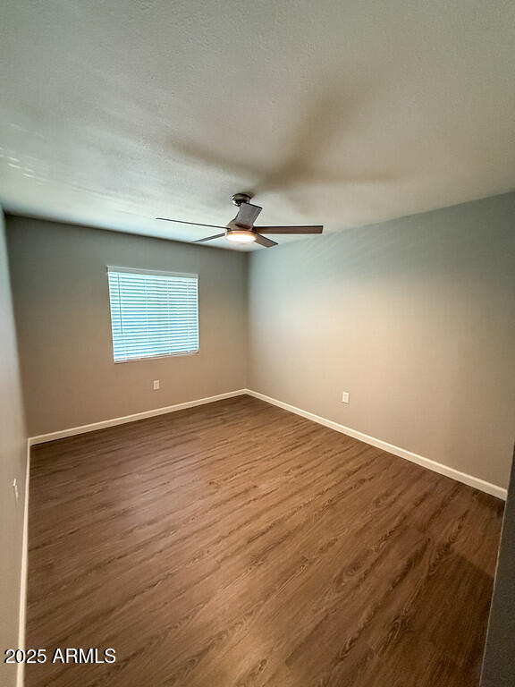 127 South Outpost Road, Unit 3 Apache Junction, AZ 85119 - Photo 3 of 6 an empty room with wooden floor cabinet and windows