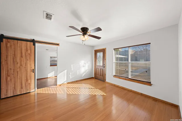 a view of an empty room with a window and wooden floor
