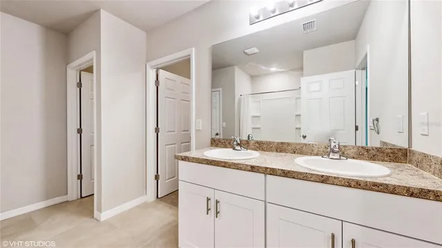 a bathroom with a granite countertop double sink and a mirror