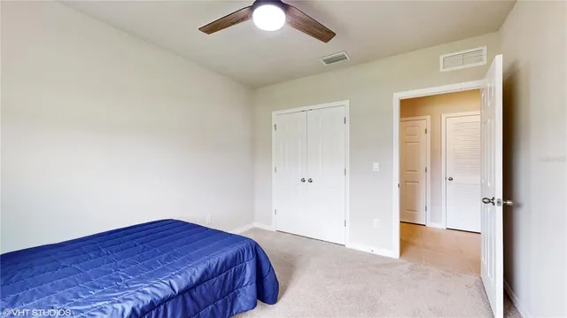 an empty room with a bed and a chandelier fan