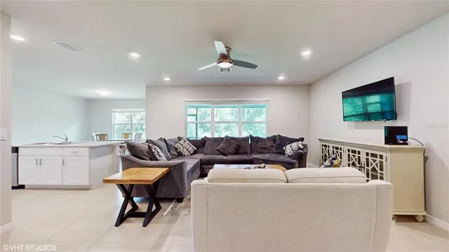 a living room with furniture a flat screen tv and kitchen view
