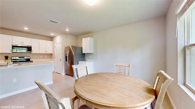 a kitchen with a table chairs refrigerator and microwave