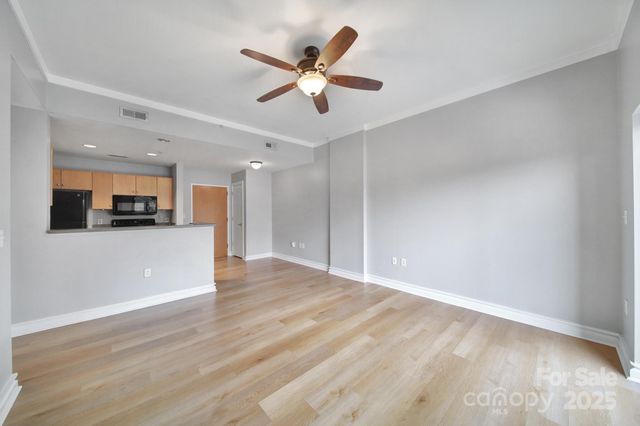 a view of an empty room with kitchen appliances and a ceiling fan