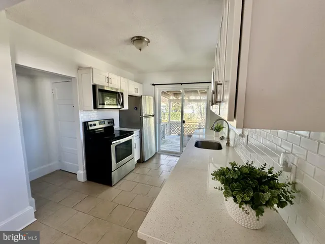 a living room with stainless steel appliances furniture a rug and a view of kitchen