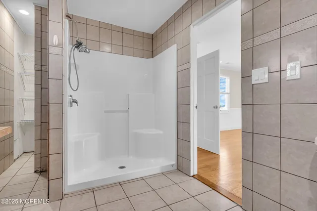 a view of an empty room with wooden floor and a ceiling fan