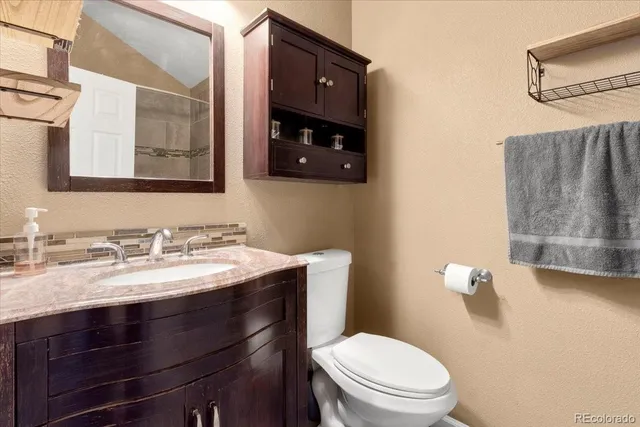 a bathroom with a granite countertop toilet sink and mirror