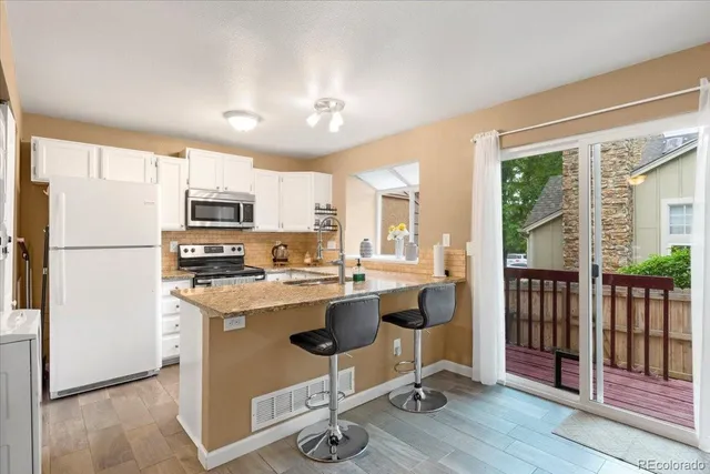 a view of a kitchen with kitchen island a refrigerator a stove a sink dishwasher with a dining table and chair