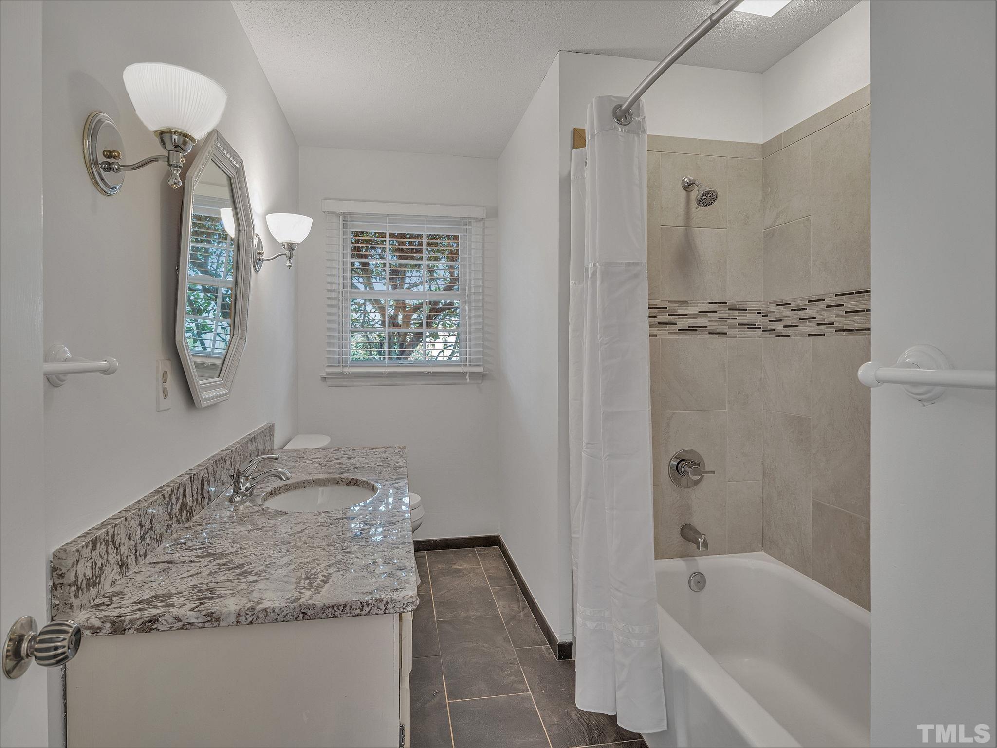 1509 Windbur Place Raleigh, NC 27609 - Photo 31 of 39 a bathroom with a granite countertop sink a toilet and shower