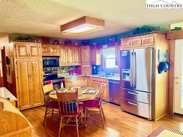 191 Welch Road Lansing, NC 28643 - Photo 9 of 41 a kitchen with stainless steel appliances granite countertop a dining table chairs refrigerator and sink