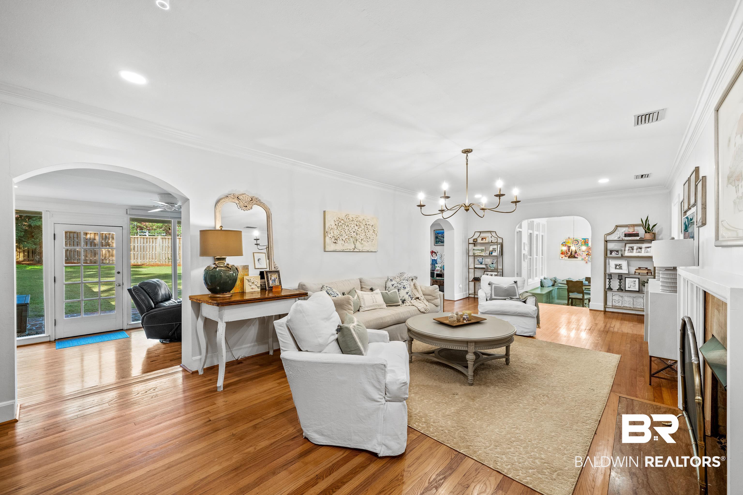 141 Myrtlewood Lane Mobile, AL 36608 - Photo 17 of 44 Living room featuring a notable chandelier, wood finished floors, visible vents, arched walkways, and ornamental molding