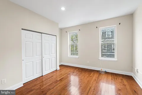 an empty room with wooden floor and windows