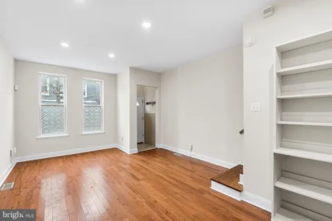 a view of empty room with wooden floor and fan