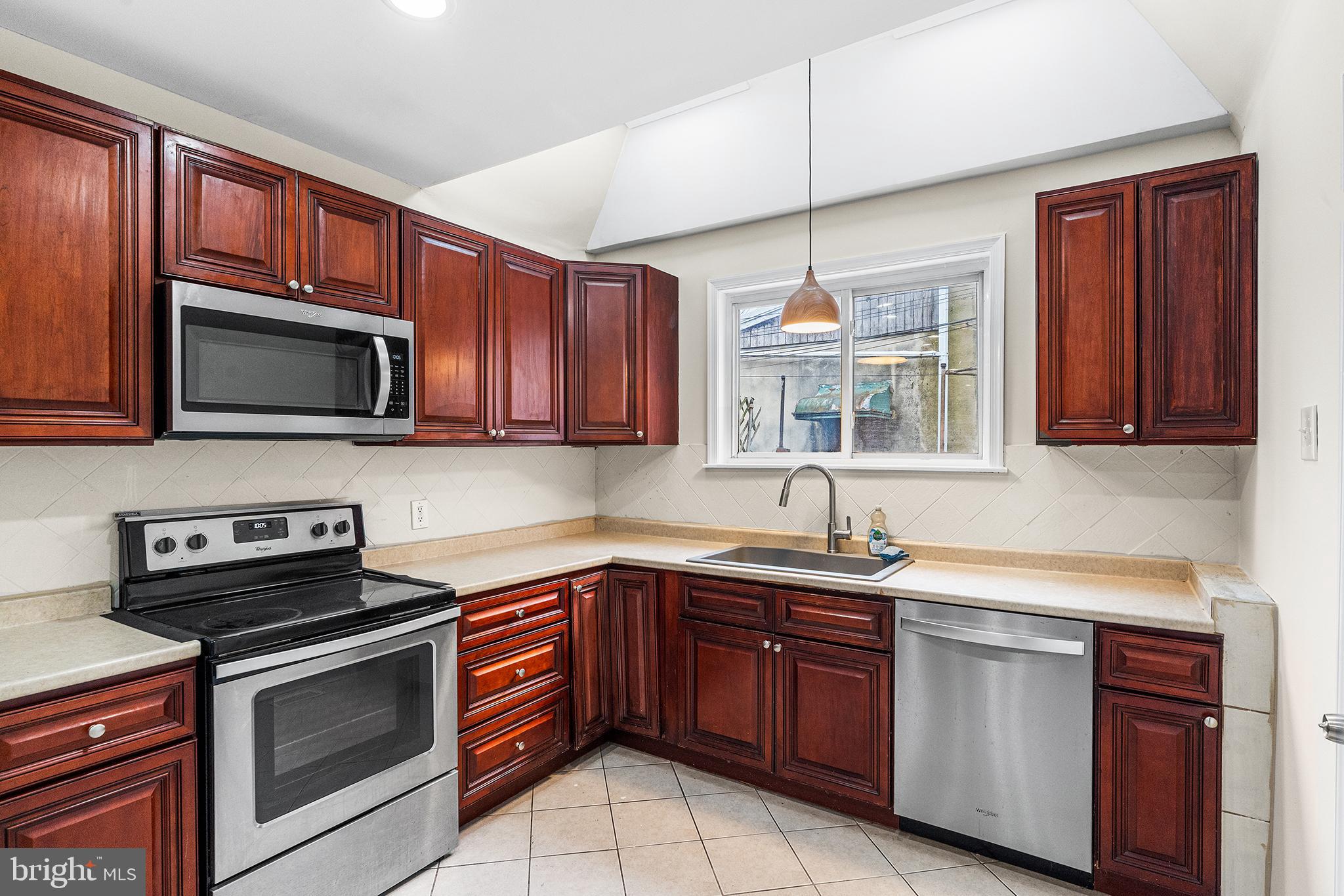 1538 Tasker Street Philadelphia, PA 19145 - Photo 9 of 23 a kitchen with stainless steel appliances granite countertop a sink a stove a microwave and wooden cabinets