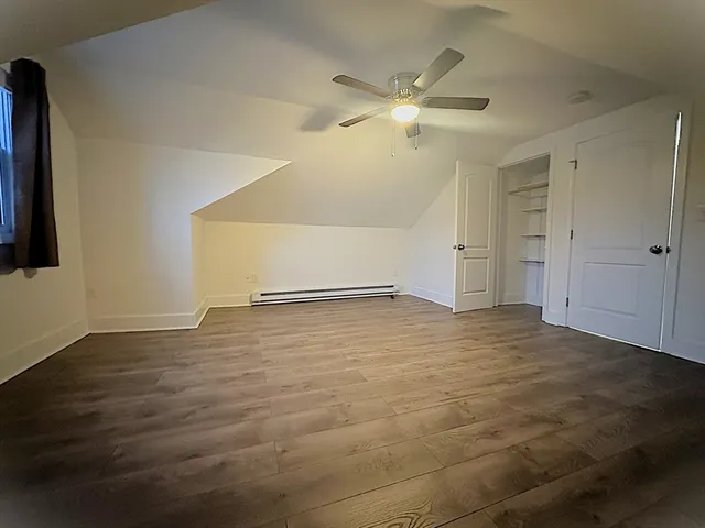 an empty room with wooden floor and fan