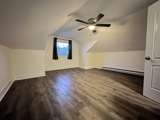 an empty room with wooden floor chandelier fan and windows