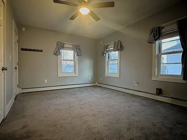 an empty room with windows and fan