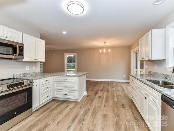 a kitchen with stainless steel appliances granite countertop a stove a sink and a microwave