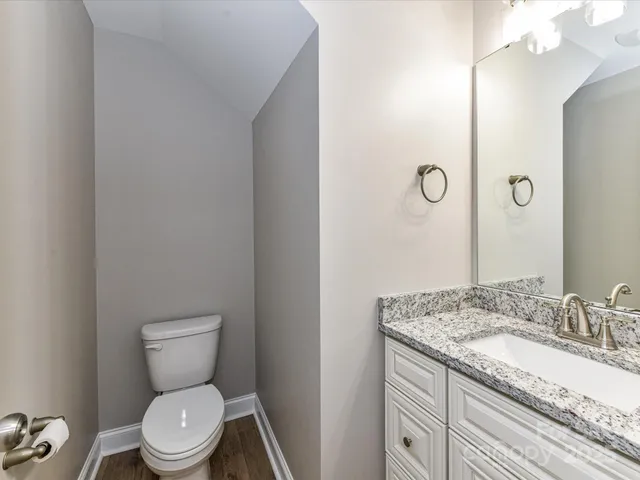 a bathroom with a granite countertop toilet sink and mirror